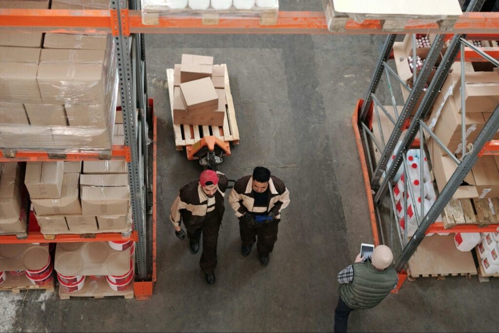 Three men in a warehouse carrying stock and calculating inventory